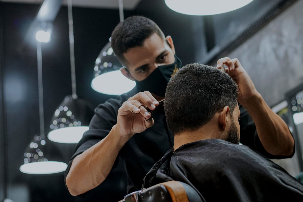 Photo of a Man in a Black Dress Shirt Cutting Another Man's Hair